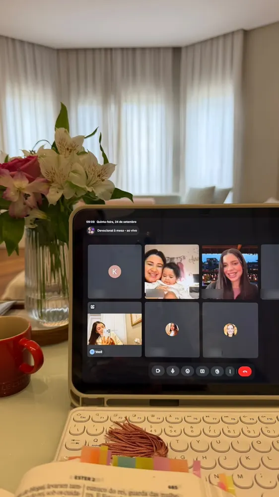 Devocional à Mesa ao vivo no tablet, com participantes na chamada e flores ao lado