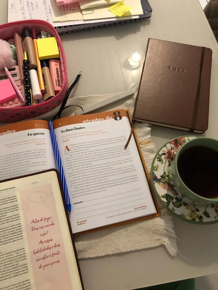 Devocional aberto sobre a mesa, com estojo, agenda e xícara de chá